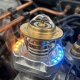 Automotive thermostat component with metallic surfaces in engine bay with orange and blue lighting effects