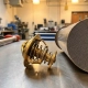 Precision automotive thermostat with brass actuator beside honeycomb catalytic converter on metal workbench in engineering lab