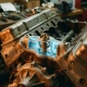 Car engine block cutaway showing precision thermostat in cooling system with amber lighting and blue coolant passages