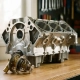 Engine block with thermostat component on workshop table, showing brass and steel details under soft lighting