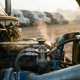 Modern truck engine bay with precision thermostat component, steam rising from warm engine block, commercial fleet in background