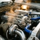 Turbocharged engine bay showing chrome intercooler pipes, heat exchangers, thermostats and temperature sensors with steam rising from hot metal surfaces
