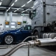 Family sedan and commercial truck connected to emission testing equipment in automotive facility with LED lighting