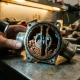 Cross-sectioned automotive thermostat housing showing severely clogged coolant passages filled with rust-colored sediment and mineral deposits on workshop bench
