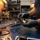 Mechanic's hands examining a precision thermostat component on workbench with diagnostic tools in automotive workshop