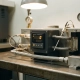 Precision thermostat mounted in a laboratory test rig with calibrated temperature probes, pressure gauges, and fluid flow meters on a steel workbench.