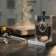 Precision thermostat component clamped in a stainless steel testing fixture, surrounded by temperature calibration instruments and measurement probes.