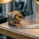 Precision thermostat component with oxidized metal electrical contacts on an industrial test bench, calibration thermometer visible nearby.