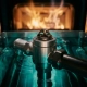 Precision thermostat valve submerged in flowing blue-green engine coolant with amber heat radiating from a blurred combustion chamber behind it.