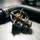 Cross-sectioned engine thermostat revealing wax element and machined metal housing, with coolant hose visible on steel surface.