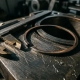 Worn piston ring on scored engine cylinder surface with metallic debris, caliper gauge alongside for scale, macro workshop lighting.