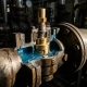 Cross-section of a precision thermostat valve on an industrial pipe, showing coolant flow around a brass wax-element actuator with dramatic side lighting.